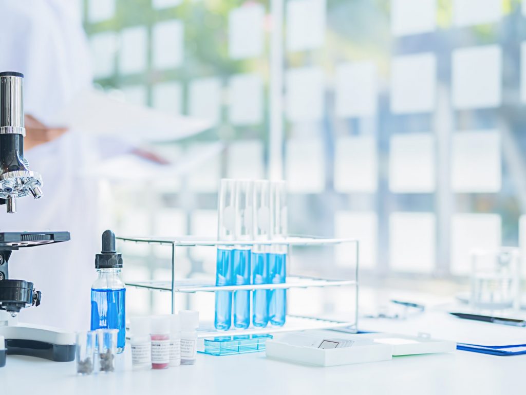 Medical or scientific researcher or man doctor looking at a test tube of clear solution in a laboratory